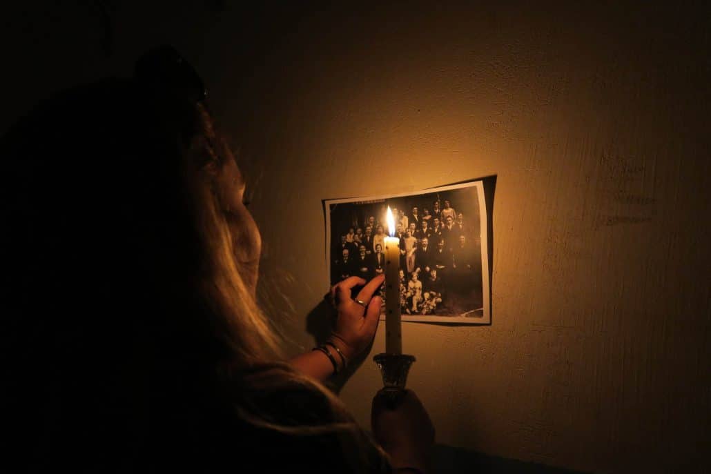 Une bougie éclaire une vieille photo de famille accrochée au mur, dans le noir
