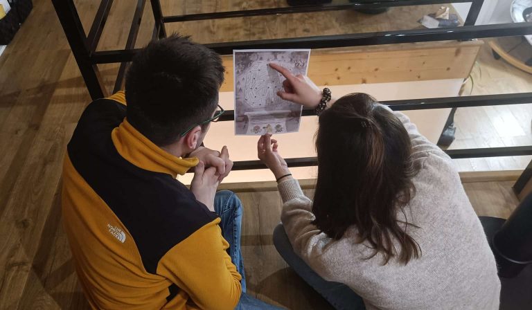 Deux joueurs penchés sur une énigme imprimée du kit Le tournoi des sorciers