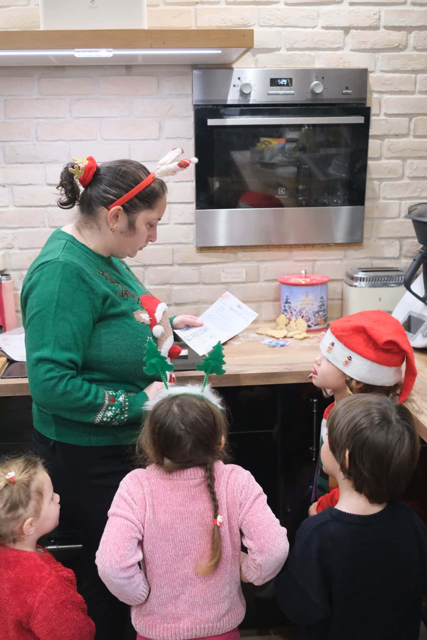 Une mère lit la lettre d'ouverture du jeu à trois enfants en tenue de Noël