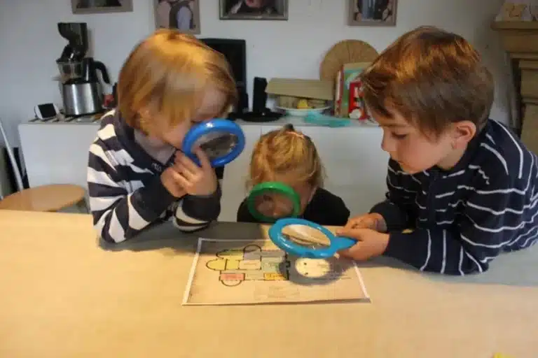Deux enfants observent une énigme à la loupe