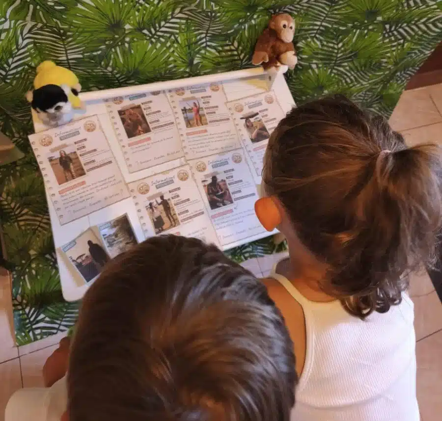 Deux enfants lisent les fiches des suspects posées dans la savane, pendant l'escape game en famille Mission Safari