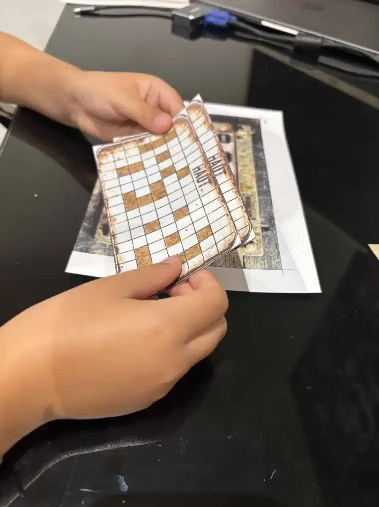 Mains d'enfant qui remplissent une grille d'énigme imprimée