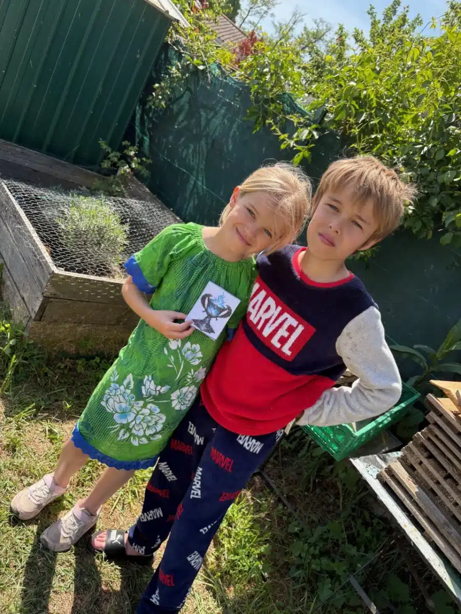 Dos ninos sonrientes con una tarjeta de pista en la mano